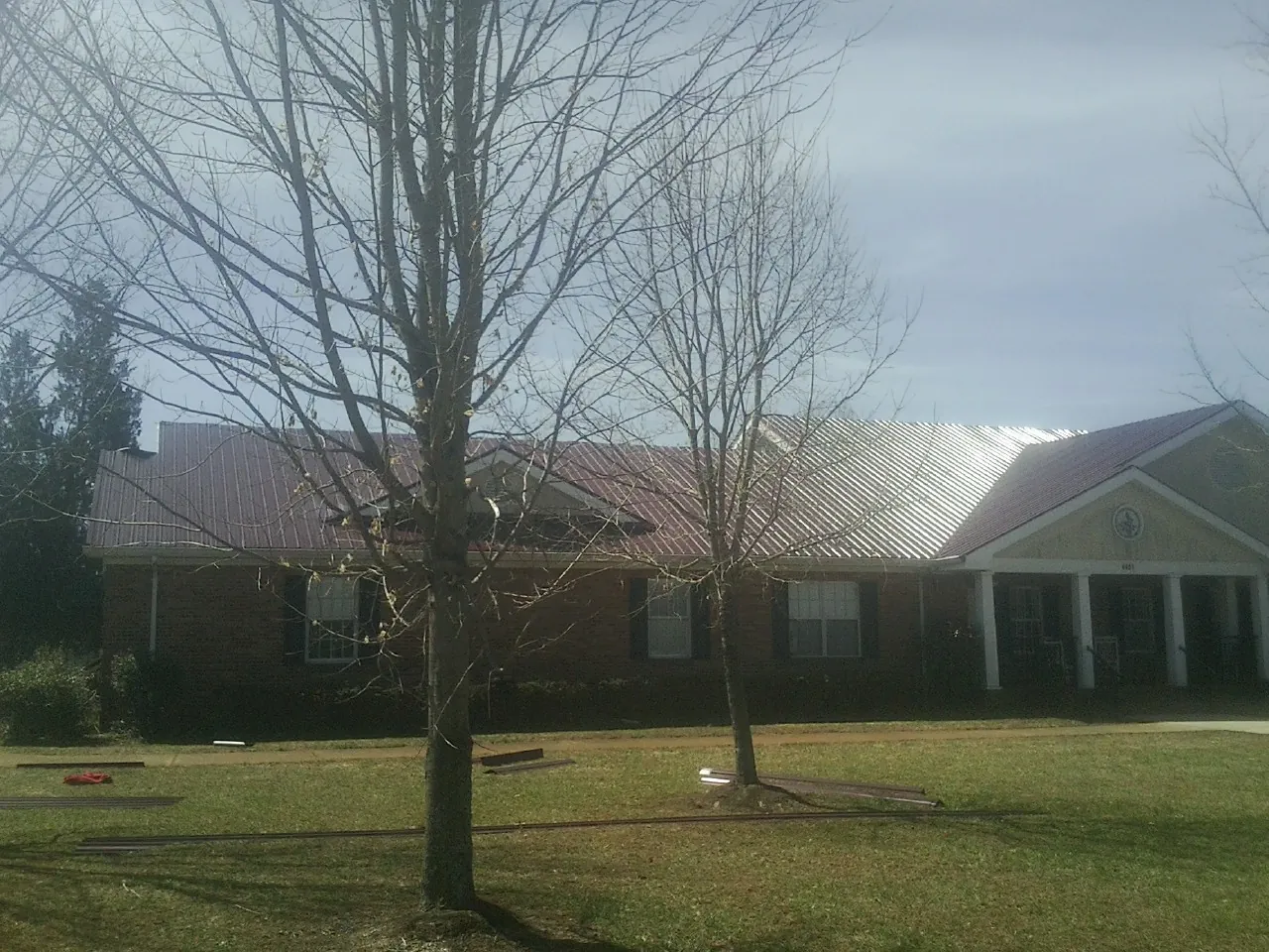 Red metal roof on a brick building seen from the front lawn in Alvo