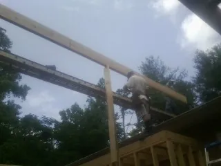 Carpenter setting a ridge beam over a new addition frame — Ice Dam Removal by Roofing Brothers in Alvo