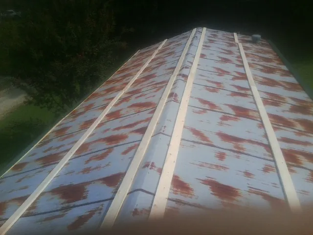 Rusted metal roof panels with new wood purlins before replacement — Storm Damage Roof Repair in Alvo by Roofing Brothers