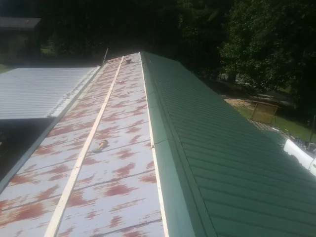 Old rusted panels beside newly installed green metal roofing — Wind Damage Roof Repair by Roofing Brothers in Alvo