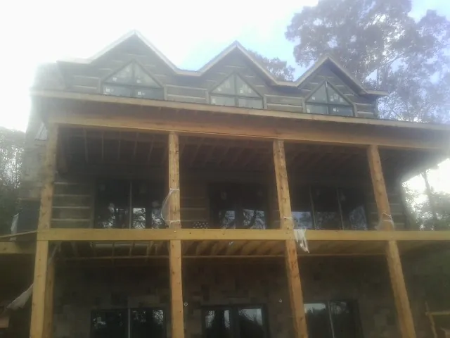 Dormers and porch framing on a large log home under construction — Roof Coating work by our crew in Alvo