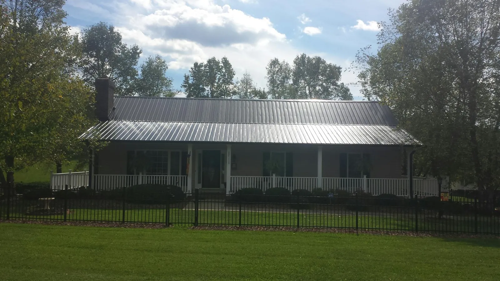 Gray metal roof on a brick ranch with a full width front porch — Gutter Guard Installation work by our crew in Alvo
