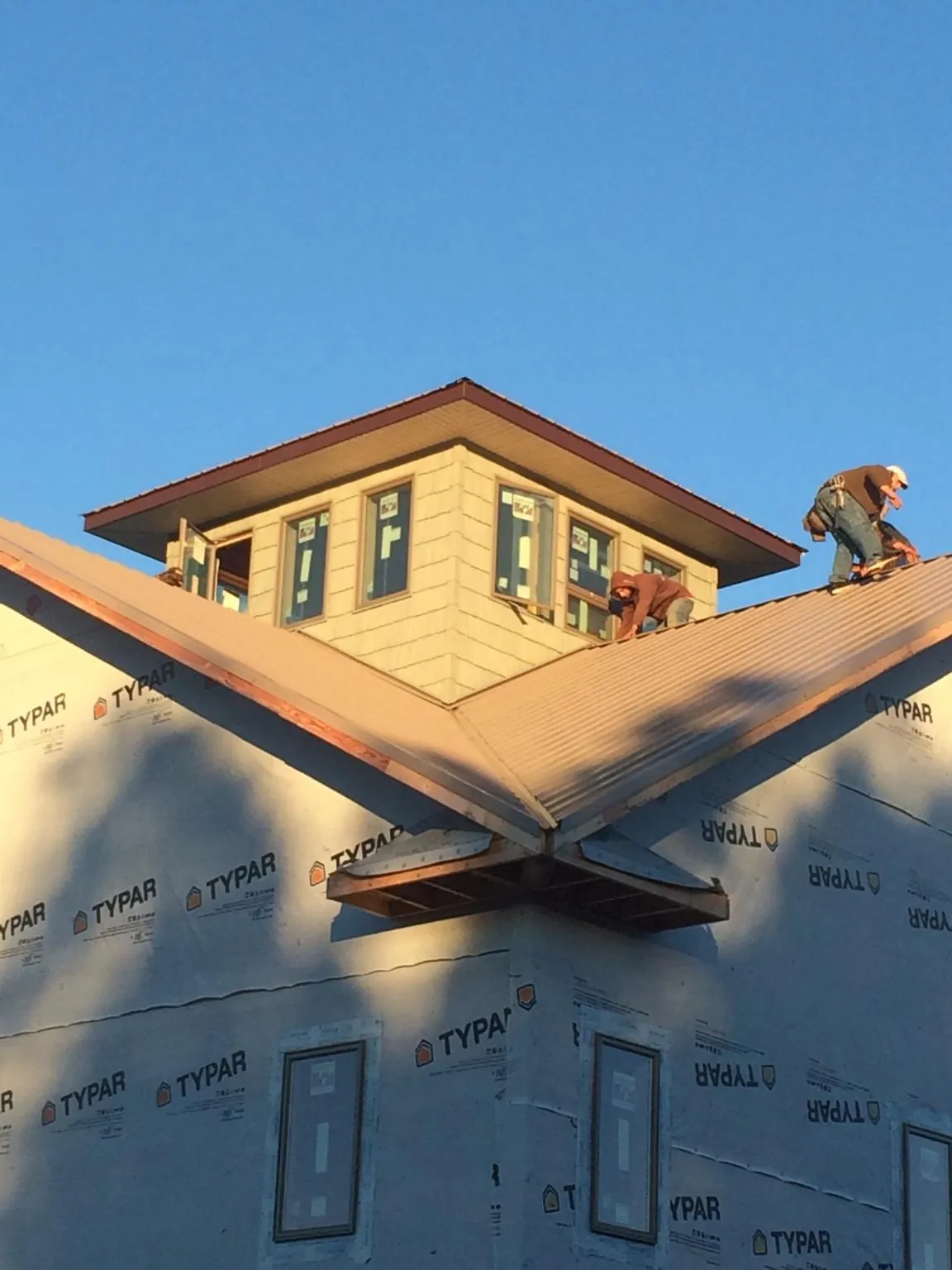 Roofers working around a rooftop cupola on a new metal roof at sunset — Roof Waterproofing in Alvo by Roofing Brothers